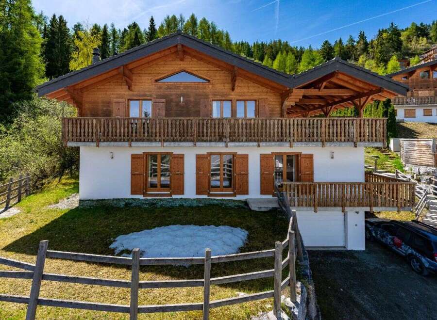 Experience luxury mountain living in this stunning chalet, featuring a spacious wooden balcony perfect for enjoying breathtaking alpine views.