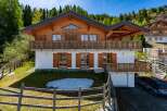 Experience luxury mountain living in this stunning chalet, featuring a spacious wooden balcony perfect for enjoying breathtaking alpine views.