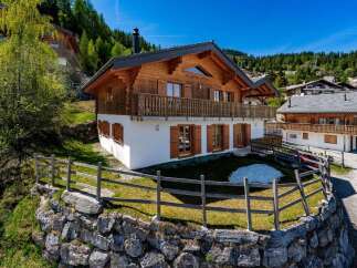 Experience alpine living in this stunning wooden chalet, nestled on a hillside with breathtaking mountain views.