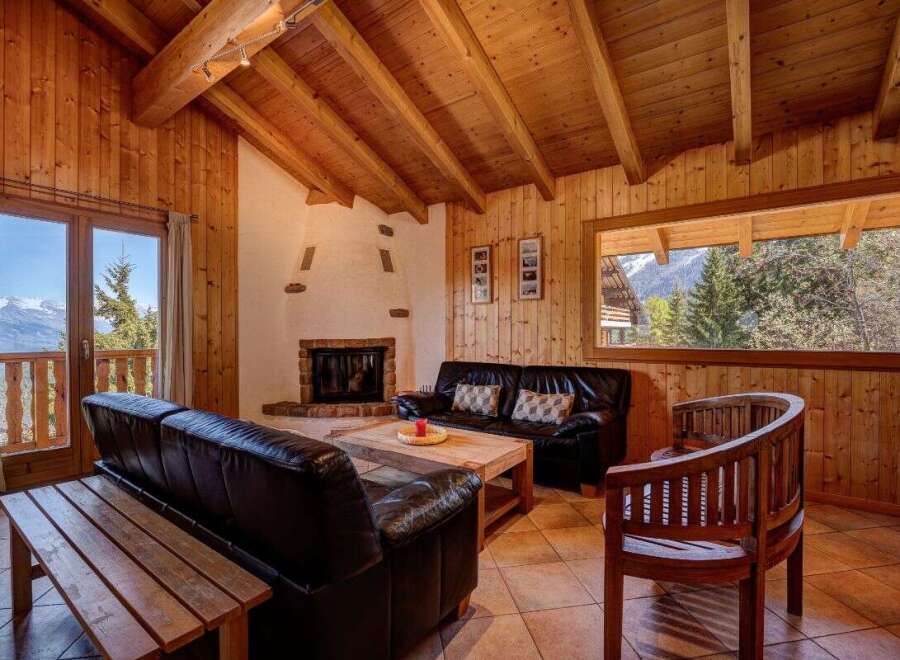Experience cozy mountain living in this charming wood-paneled living room, featuring a rustic fireplace and comfortable leather seating.