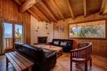 Experience cozy mountain living in this charming wood-paneled living room, featuring a rustic fireplace and comfortable leather seating.