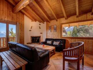 Experience cozy mountain living in this charming wood-paneled living room, featuring a rustic fireplace and comfortable leather seating.