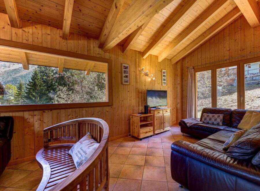 Experience rustic charm in this cozy wooden cabin living room, featuring a large picture window with stunning mountain views.