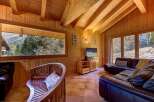Experience rustic charm in this cozy wooden cabin living room, featuring a large picture window with stunning mountain views.