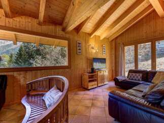 Experience rustic charm in this cozy wooden cabin living room, featuring a large picture window with stunning mountain views.
