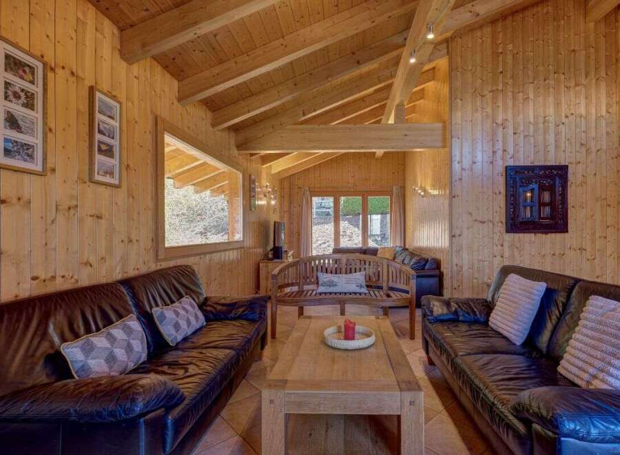 Experience rustic charm in this cozy living room, featuring warm wood paneling and exposed beams.