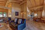 Experience rustic charm in this spacious wooden chalet, featuring a cozy living area with a leather sofa and a well-equipped open-plan kitchen and dining space.