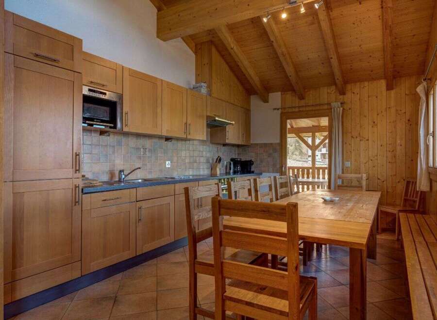 Experience cozy living in this charming kitchen and dining area, featuring warm wooden cabinetry and a spacious dining table perfect for family meals.