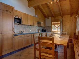 Experience cozy living in this charming kitchen and dining area, featuring warm wooden cabinetry and a spacious dining table perfect for family meals.