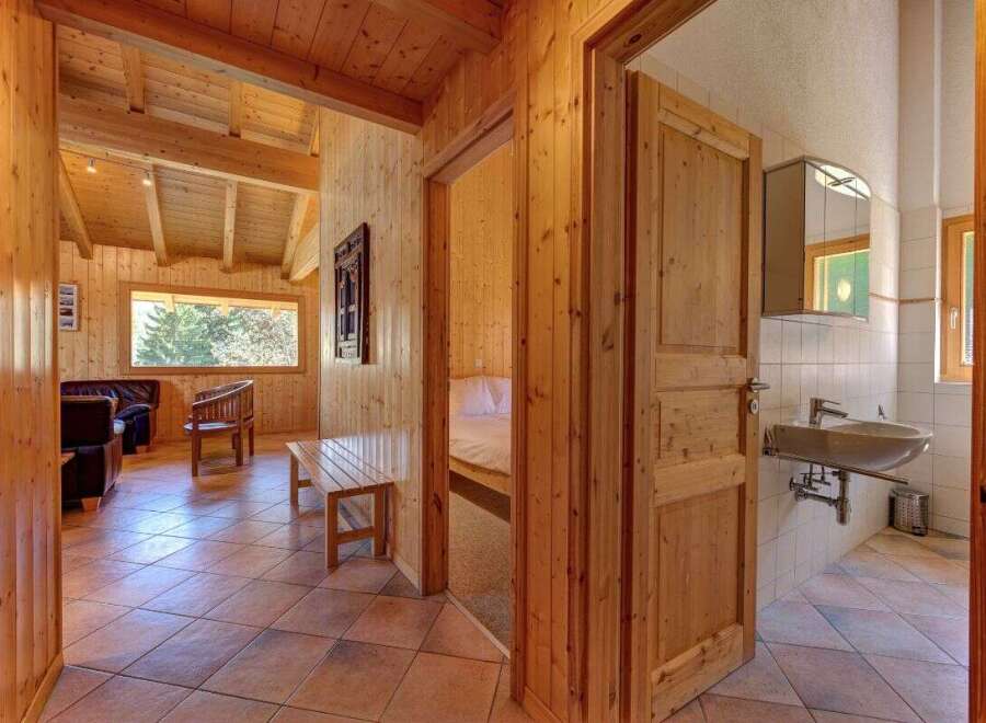Experience rustic charm in this beautifully appointed wooden cabin, featuring a spacious living area with comfortable seating and a large window offering scenic views.