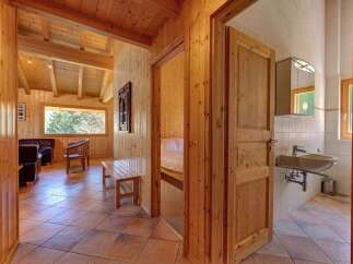 Experience rustic charm in this beautifully appointed wooden cabin, featuring a spacious living area with comfortable seating and a large window offering scenic views.