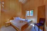 Experience cozy living in this charming wooden-paneled bedroom, featuring a comfortable queen-sized bed with crisp white linens and plush towels.