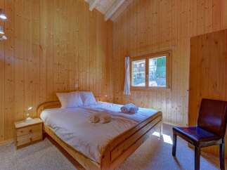 Experience cozy living in this charming wooden-paneled bedroom, featuring a comfortable queen-sized bed with crisp white linens and plush towels.