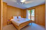 Experience cozy mountain living in this charming bedroom featuring warm, wood-paneled walls and a comfortable queen-sized bed.