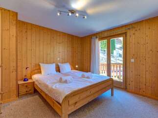 Experience cozy mountain living in this charming bedroom featuring warm, wood-paneled walls and a comfortable queen-sized bed.