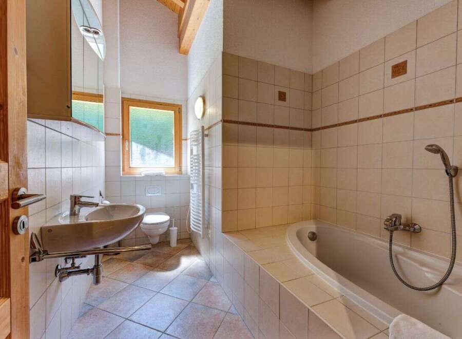 This charming bathroom features a spacious bathtub perfect for relaxing soaks, complemented by a modern sink and toilet.