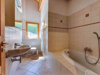 This charming bathroom features a spacious bathtub perfect for relaxing soaks, complemented by a modern sink and toilet.