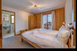 Experience cozy mountain living in this charming bedroom featuring a comfortable bed, ample wooden wardrobe, and a private balcony with stunning alpine views.