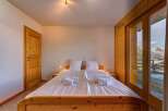 Experience breathtaking mountain views from this charming bedroom, featuring a comfortable double bed and a large glass door leading to a private balcony.