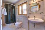 This charming bathroom features a modern glass-enclosed shower, a sleek wall-mounted toilet, and a stylish vanity with a large oval mirror.
