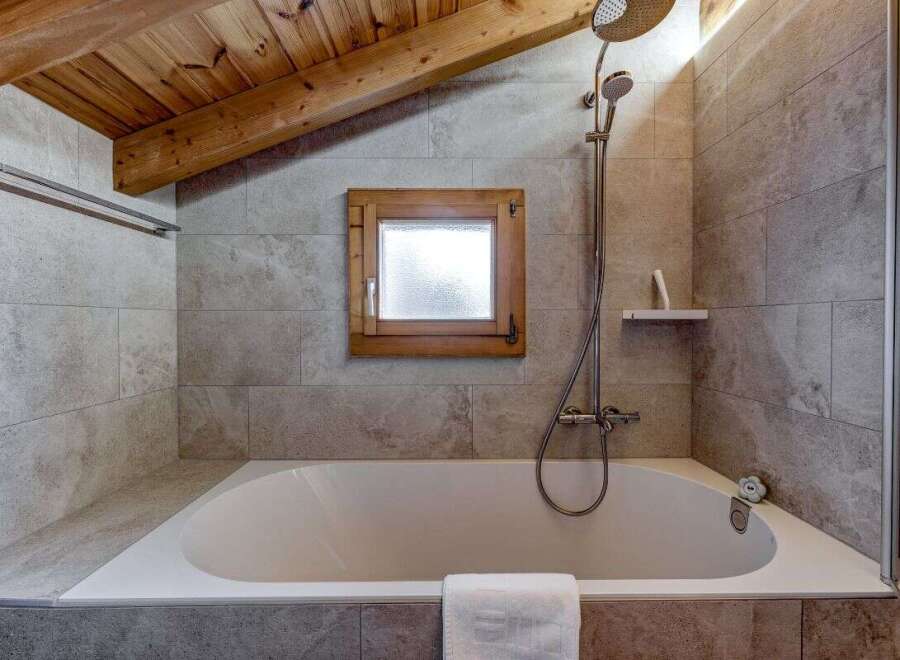 This charming bathroom features a cozy ambiance with its wooden ceiling and natural light.