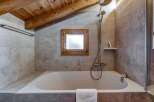 This charming bathroom features a cozy ambiance with its wooden ceiling and natural light.