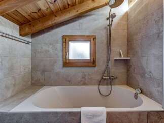 This charming bathroom features a cozy ambiance with its wooden ceiling and natural light.