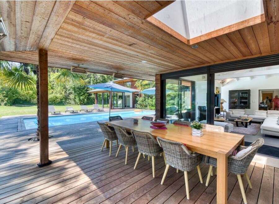 Experience luxury living with this stunning property featuring an outdoor dining area overlooking a sparkling pool.
