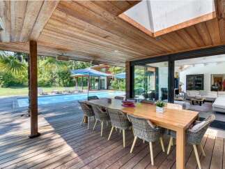 Experience luxury living with this stunning property featuring an outdoor dining area overlooking a sparkling pool.