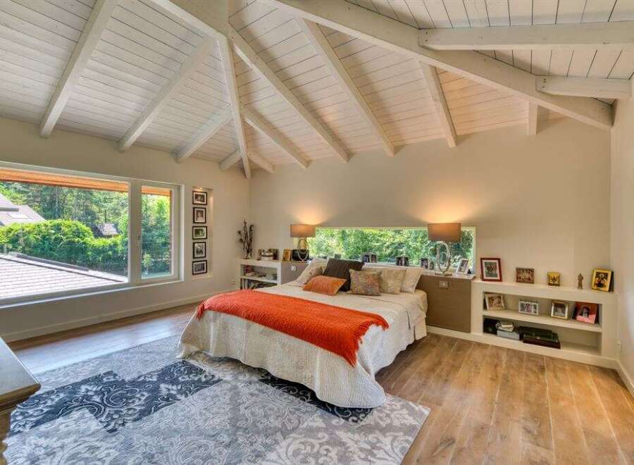 This stunning bedroom boasts a unique architectural design with a vaulted ceiling and exposed beams, creating a spacious and airy atmosphere.