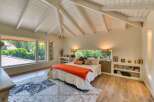 This stunning bedroom boasts a unique architectural design with a vaulted ceiling and exposed beams, creating a spacious and airy atmosphere.