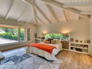 This stunning bedroom boasts a unique architectural design with a vaulted ceiling and exposed beams, creating a spacious and airy atmosphere.
