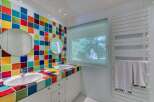 This vibrant bathroom features a unique design with colorful tiled walls and countertops, creating a cheerful and inviting atmosphere.