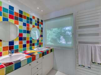 This vibrant bathroom features a unique design with colorful tiled walls and countertops, creating a cheerful and inviting atmosphere.