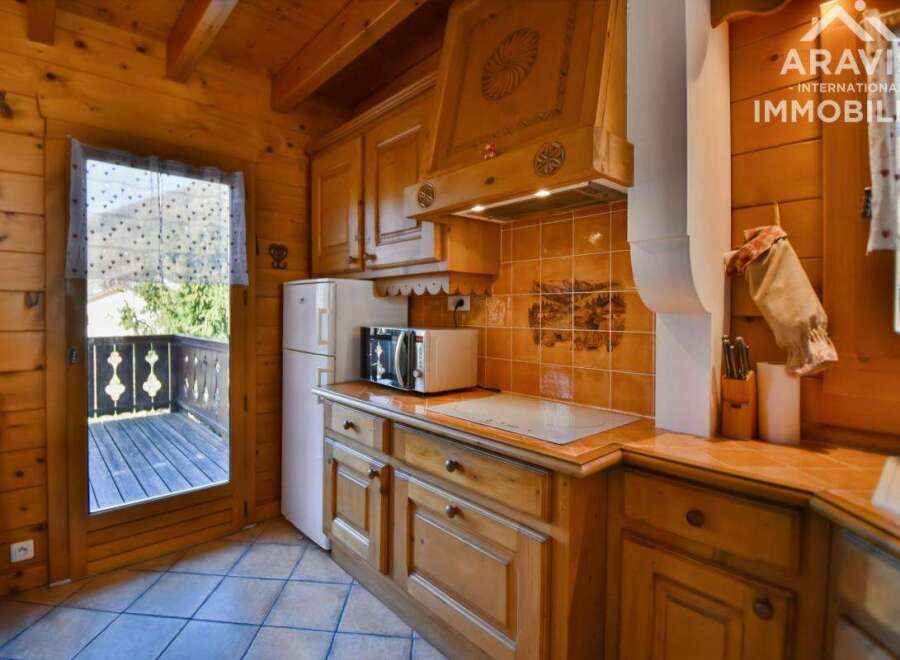 Discover the charm of this cozy kitchen, featuring warm wooden cabinetry and a modern microwave.