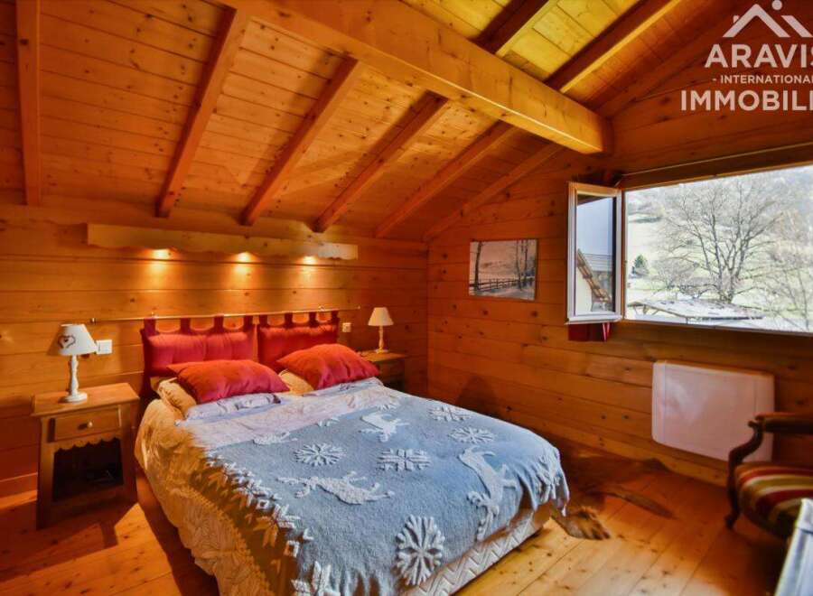 Discover the charm of this cozy bedroom, featuring warm wooden walls and a unique sloped ceiling.