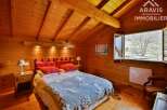 Discover the charm of this cozy bedroom, featuring warm wooden walls and a unique sloped ceiling.