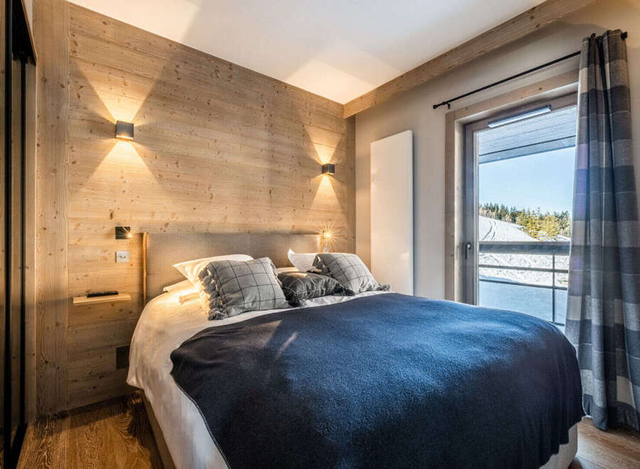 Experience the warmth of this cozy bedroom featuring a stunning wooden accent wall and modern lighting.