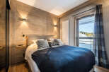 Experience the warmth of this cozy bedroom featuring a stunning wooden accent wall and modern lighting.