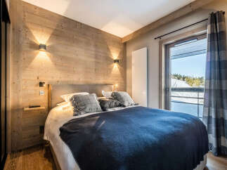 Experience the warmth of this cozy bedroom featuring a stunning wooden accent wall and modern lighting.