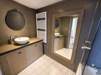 Step into this stylish bathroom, featuring a modern design with a sleek sink and a large mirror.