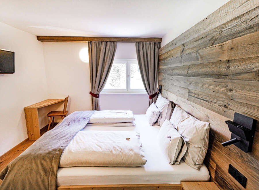 Experience rustic charm and modern comfort in this inviting bedroom, featuring a cozy bed with plush linens and a unique wooden accent wall.