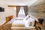 Experience rustic charm and modern comfort in this inviting bedroom, featuring a cozy bed with plush linens and a unique wooden accent wall.