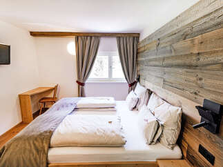 Experience rustic charm and modern comfort in this inviting bedroom, featuring a cozy bed with plush linens and a unique wooden accent wall.