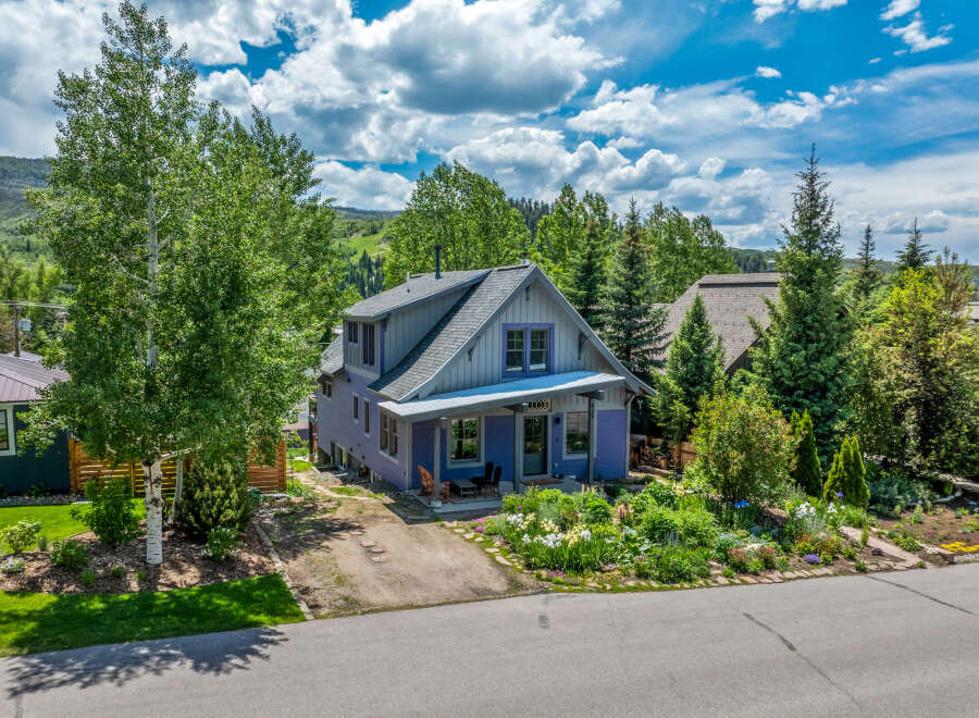 Charming purple home nestled amongst mature trees and vibrant gardens.