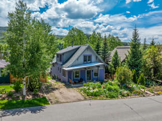 Charming purple home nestled amongst mature trees and vibrant gardens.