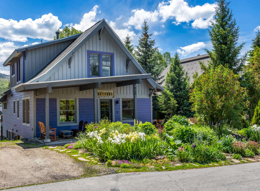 Charming mountain home featuring a vibrant purple exterior and a welcoming covered porch.