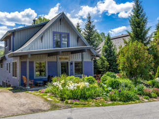 Charming mountain home featuring a vibrant purple exterior and a welcoming covered porch.