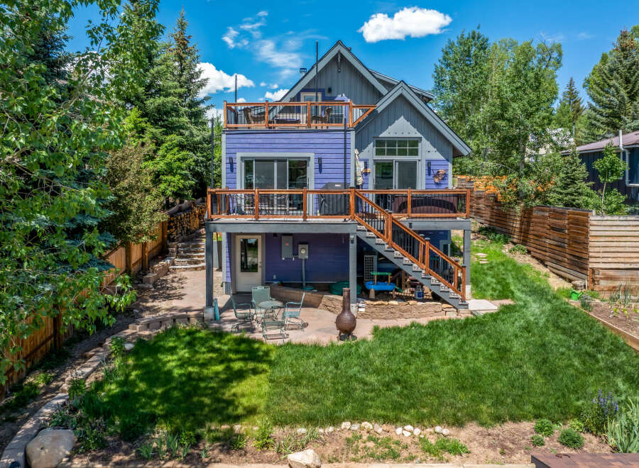 Discover this charming multi-level home featuring a vibrant purple exterior and multiple decks perfect for outdoor living.