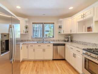 Step into this stunning kitchen, featuring sleek stainless steel appliances and pristine white cabinetry.
